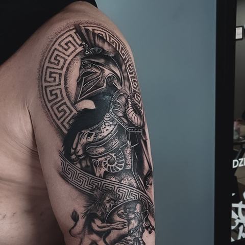 A detailed Spartan warrior occupies the shoulder and upper arm, framed by Greek ornament and rendered with intricate armour textures and strong tonal depth