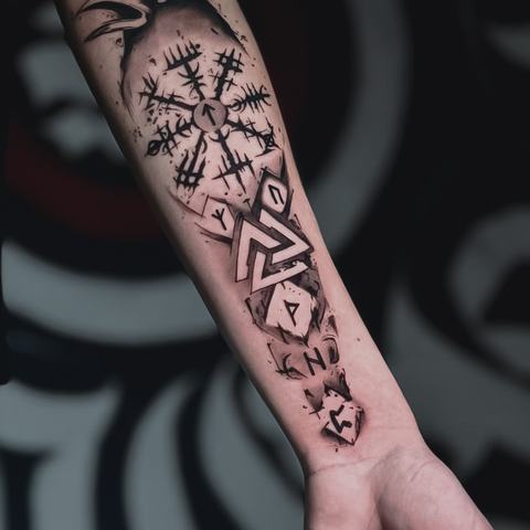 Abstract symbols and angular marks fill the inner forearm, creating a vertical blackwork design with rune-inspired elements and expressive fragmented lines