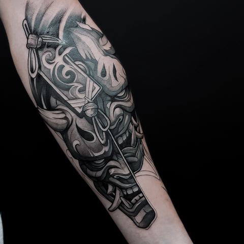A Japanese-inspired mask extends along the lower leg, combining sweeping ornamental shapes, bold contours and layered monochrome shading around the calf