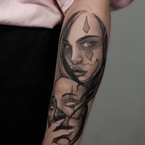 A surreal black-and-grey composition covers the upper arm, combining two female faces, symbolic facial details and layered shading with an illustrative finish
