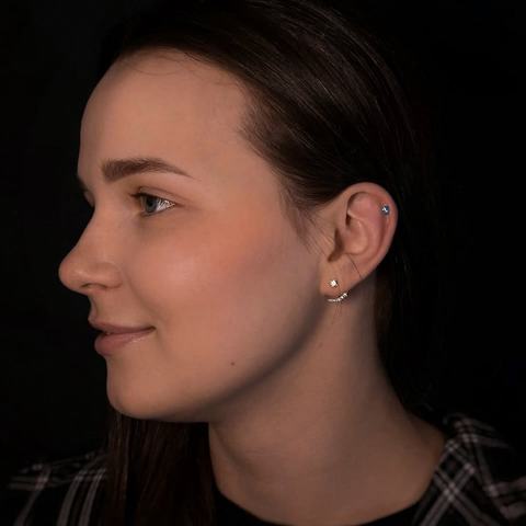 Curated ear piercing with delicate lobe jewellery and a cartilage accent for a refined everyday style. The placement follows the natural shape of the ear, giving a polished result with sterile technique and careful attention to detail.