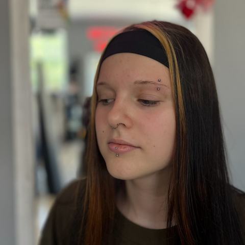 Eyebrow and labret piercing combination with a clean, balanced finish. The jewellery adds a subtle alternative accent to the face while keeping the overall look minimal and easy to wear.