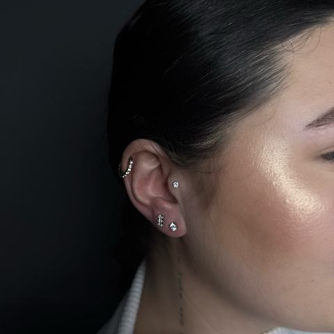 Curated ear piercing with a clean mix of lobe and cartilage jewellery. The placement creates a soft, elegant ear composition with precise installation, sterile conditions and a polished final look.