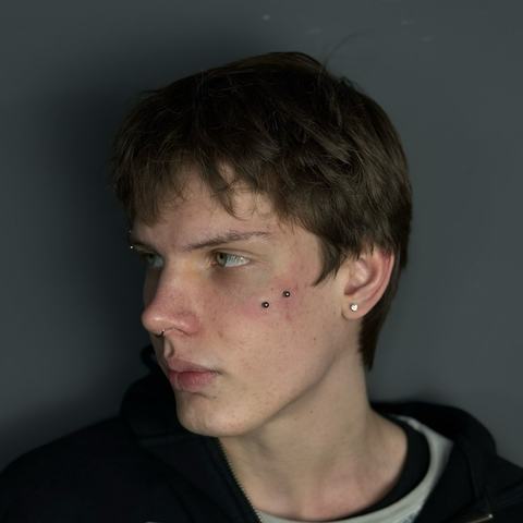 Facial piercing combination with cheek dermal accents and subtle ear jewellery for a confident alternative style. The placement adds character while keeping the look clean, precise and well-balanced.